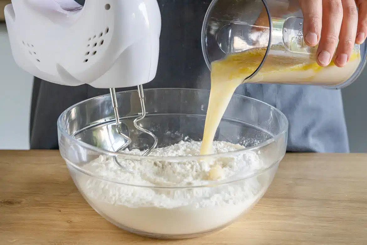 Mehl und Salz in eine große Schüssel geben. Danach die Hefe-Mischung dazugießen und mit dem Handrührgerät zu einem glatten Teig verkneten. Anschließend den Teig mit der Hand noch etwas nachkneten.