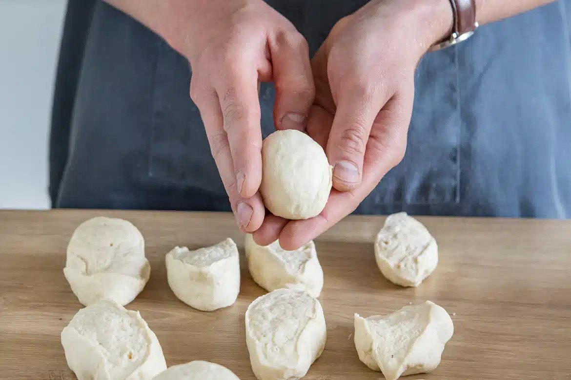 Wenn der Teig die doppelte Menge erreicht hat, diesen aus der Schüssel nehmen und 20 gleich große Kugeln formen. Diese dann zu ca. 3-5mm dicken Fladen ausrollen.