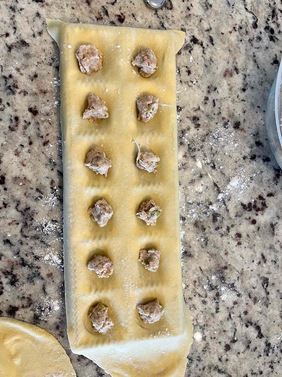 Dollop the meat filling down the pasta sheet. Keep space between each dollop or use a ravioli mold. Pat the filling down slightly. Place a second sheet on top like you’re making a sandwich.