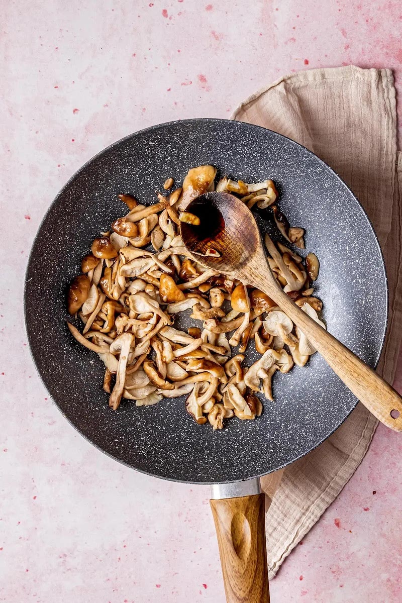 Pilze hinzufügen und 2 Minuten braten. Mit den restlichen 2 EL Tamari beträufeln, wenden und weitere 2 Minuten braten. Aus der Pfanne nehmen und beiseite stellen.