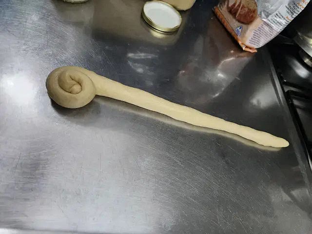 Tomar trozos de masa, hacer chorizos de masa y comenzar a enrollarlos.