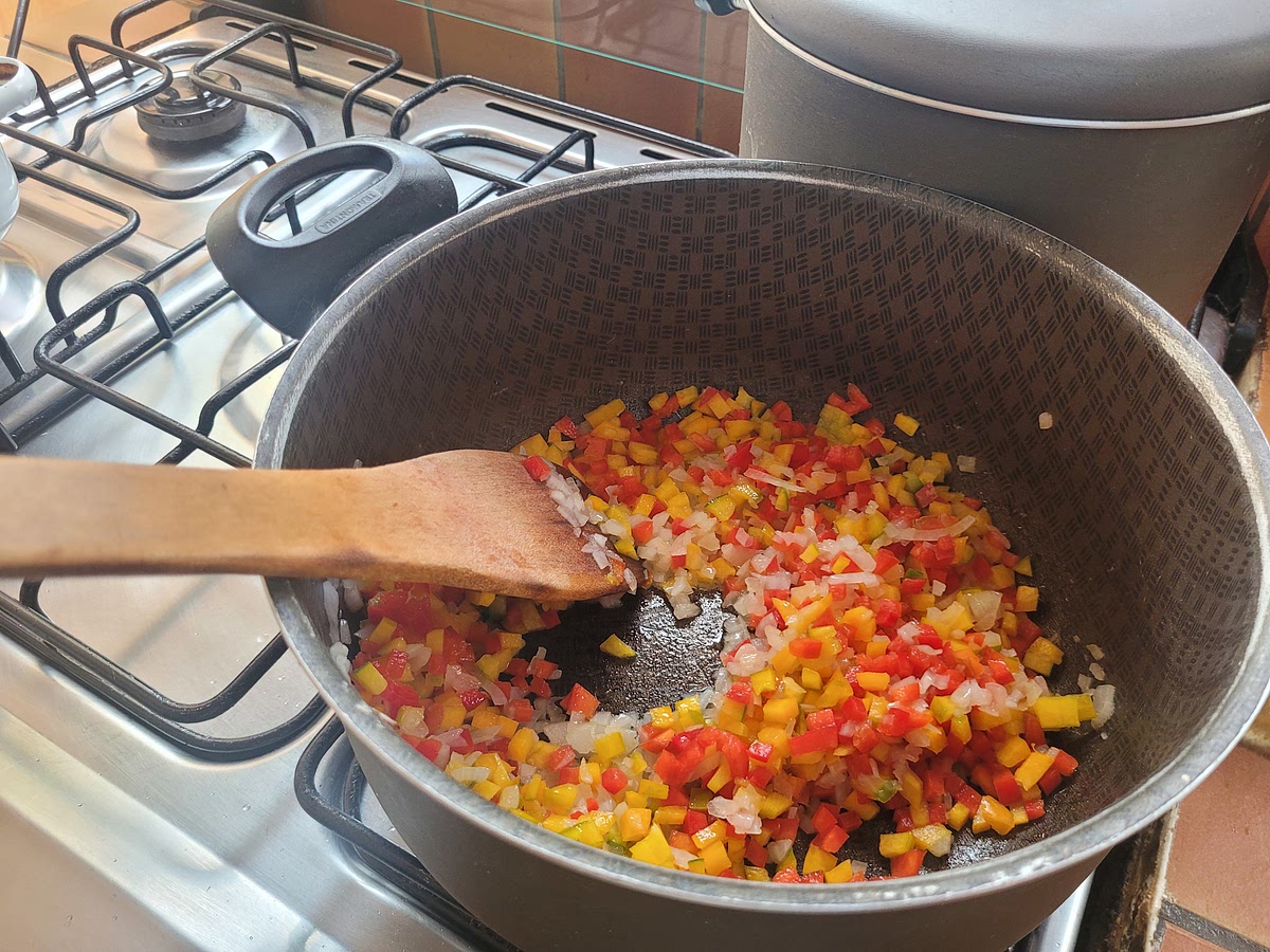 En una olla sofreir la cebolla hasta que esté brillosa, agregar los pimientos y la sal y continuar sofriendo hasta que estén cocidos