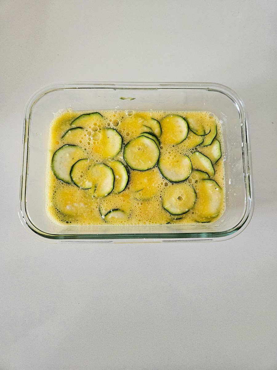 1️⃣ Preparazione del composto:
In una ciotola di vetro adatta al microonde, sbatti bene le uova con il formaggio grana, il pecorino, il sale e il pepe.
Aggiungi le rondelle sottili di zucchina e mescola.