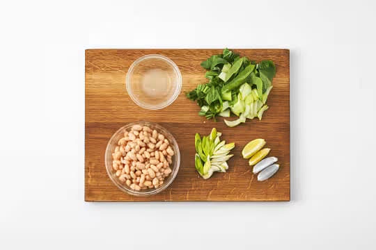 Trim the pak choi, then thinly slice widthways.
Trim the spring onion and thinly slice on an angle.
Juice half the lime, cut the other half into wedges.
Drain and rinse the butter beans in a sieve.