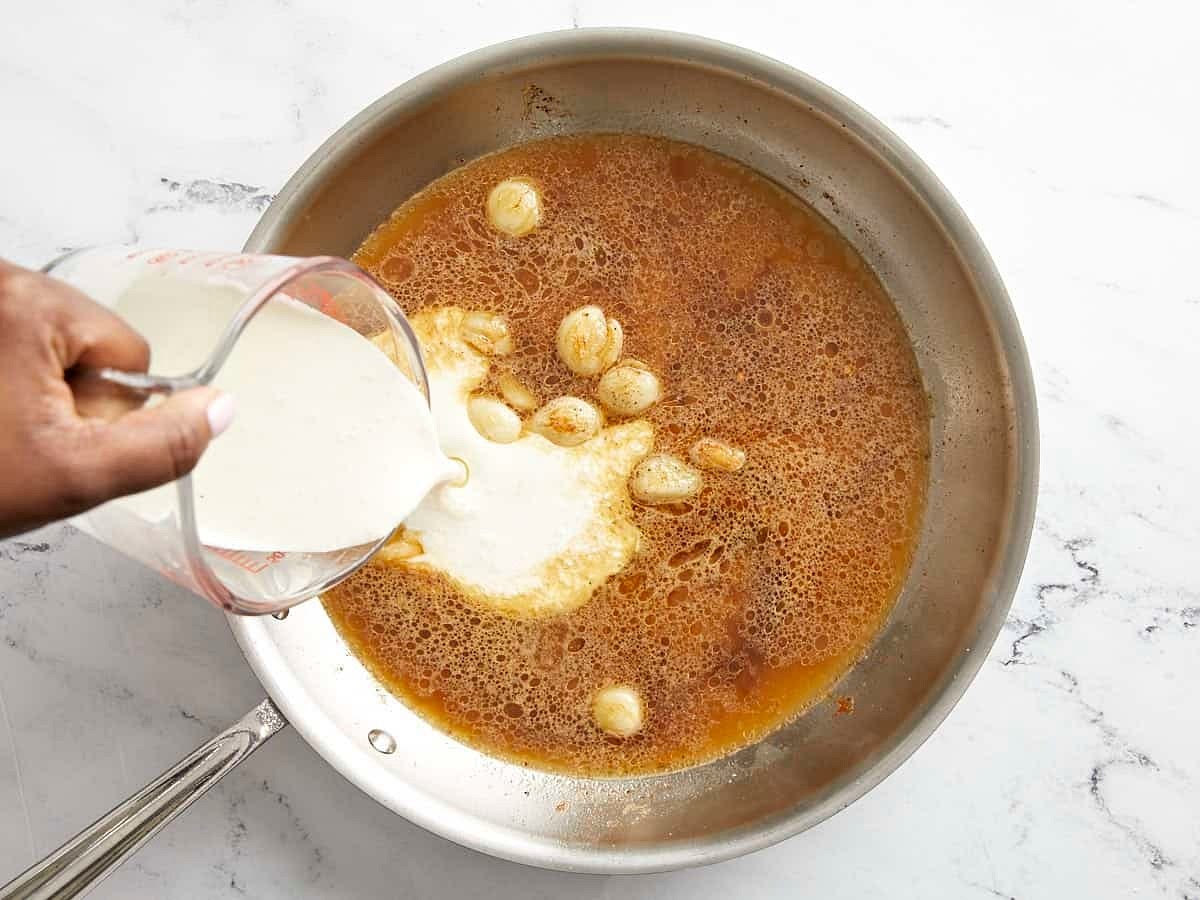 Next pour 1 cup chicken broth and 3/4 cup heavy cream into the skillet, then add 1/2 tsp garlic powder. Stir and scrape up any brown bits from the bottom of the skillet. Allow the sauce to simmer in the skillet for 8-10 minutes, or until it has reduced and thickened by about 50%.