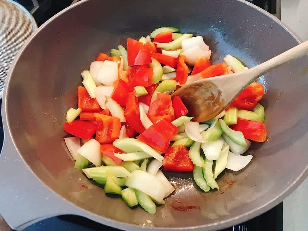 You should have some oil left in the skillet, if not, add 1 more tablespoon of oil. Saute the pepper, celery, and onion with 2 pinches of salt over medium-high heat for 1 minute.