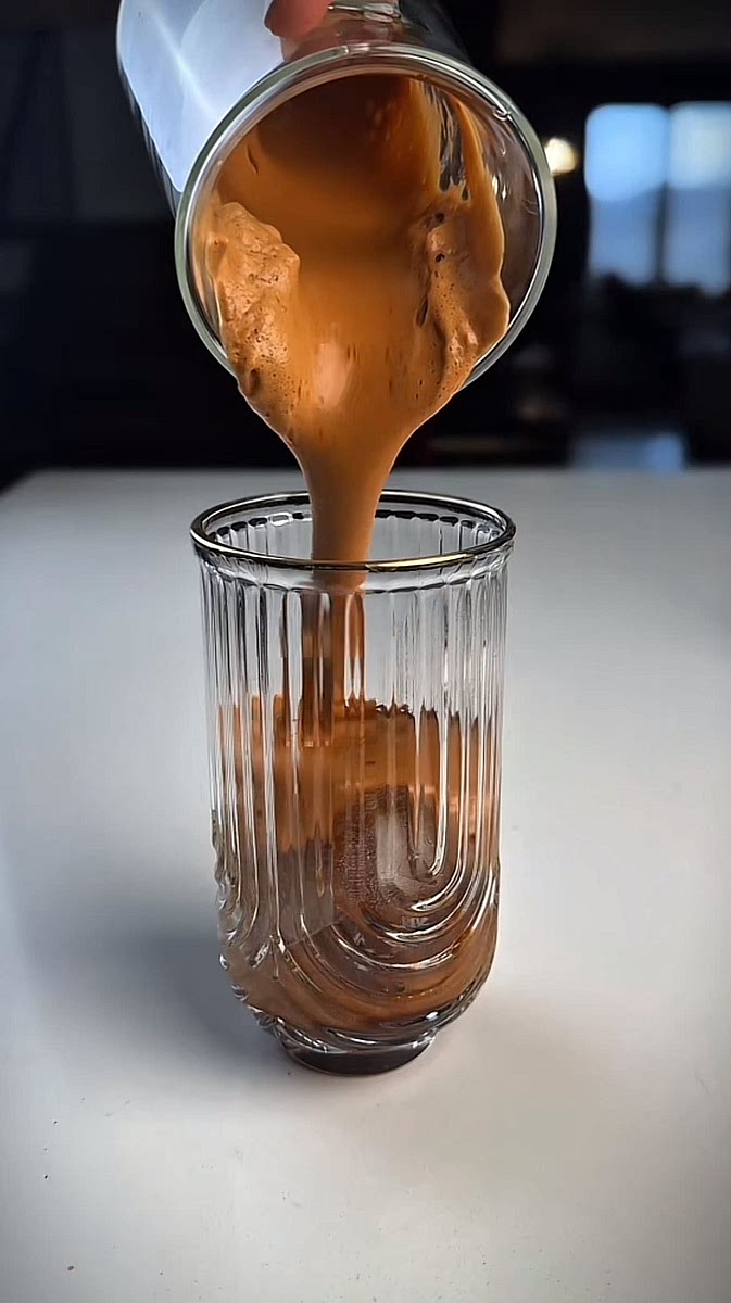 Half fill a glass with ice and add the coffee froth