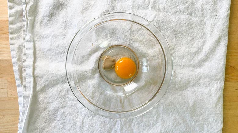 For the mayonnaise, set a medium-sized bowl over a folded towel for stability and add the egg yolk, mustard, and vinegar.
