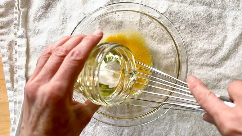 Slowly add the oil, drop by drop, while whisking constantly.