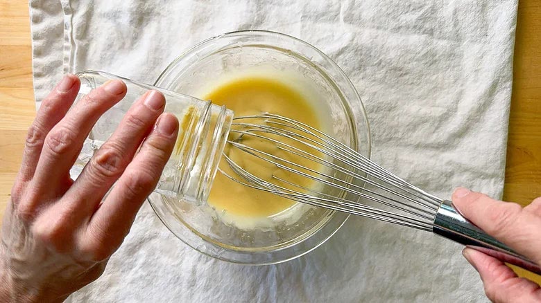 Once the mixture starts to thicken, increase the oil to a steady stream and whisk constantly to emulsify.