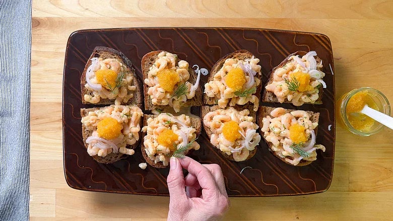 Garnish the shrimp salad with a spoonful of roe, a few shallot slices, and a sprig of fresh dill.