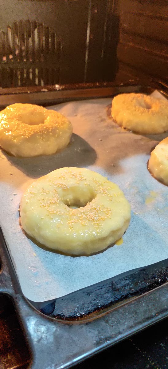 Place the blanched bagels on a baking tray lined with baking paper. If you like, brush the tops with beaten egg (1 egg) and sprinkle with sesame seeds (to taste).