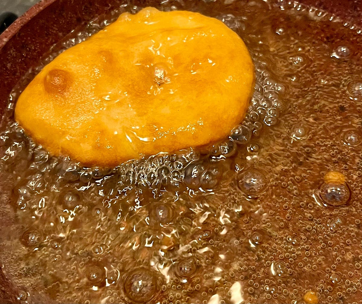 Carefully put in the hot oil and flip it regularly every few seconds until evenly golden. Take it out with a slotted spoon to drain excess oil and put it on a paper towel to dry further. If garnishing with sugar (optional) sprinkle some sugar on it at this stage.