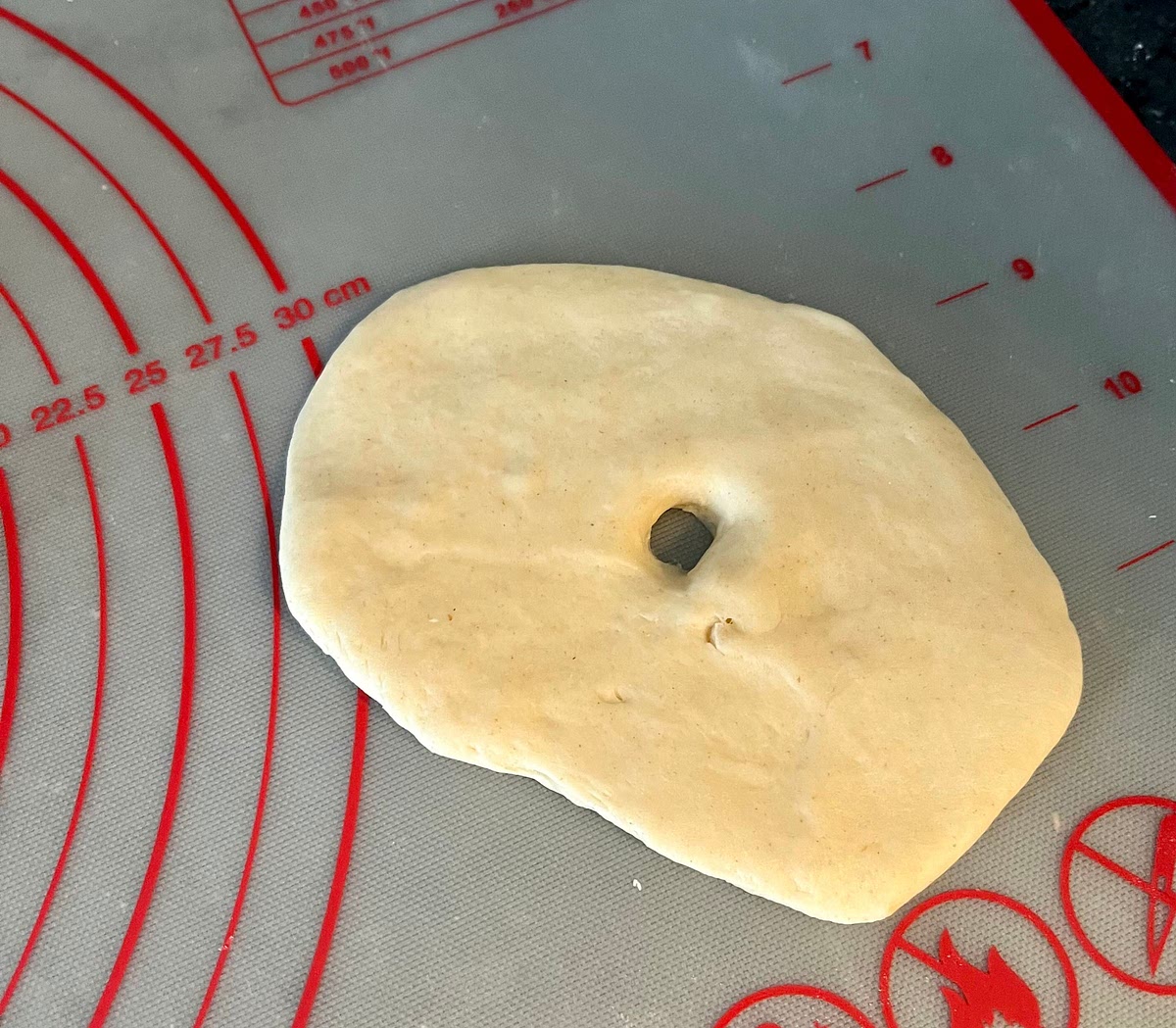 Put one of the dough balls on a working surface, flatten it with your hand and, using a rolling pin, roll it to form a disc of about 5mm thickness. Poke a hole in the middle with your finger.