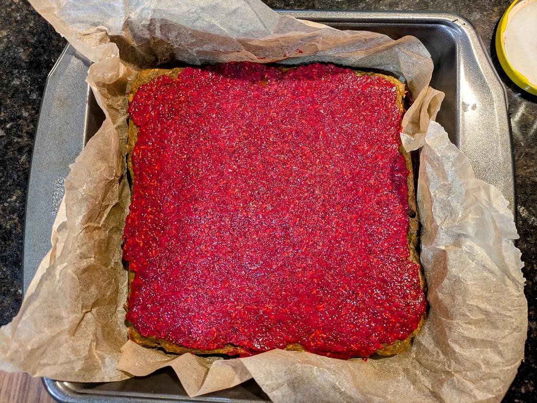 Once everything has cooled, it's time to assemble. Line a large cookie sheet with parchment paper, and place the red layer on the pan. Spread half of your jam onto the red layer. Place the yellow on top, and spread on the other half of the jam. Finally, top with the green layer