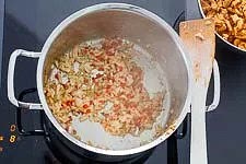 Wieder etwas Pflanzenöl in den Kochtopf geben, erhitzen und die Zwiebeln- und Paperoni-Würfel darin 2 Minuten leicht braten.