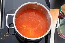 Mit den ganzen Tomaten mit Sud aus der Dose und die hälfte des Wassers mit Gemüsebrühe ablöschen. Die Tomaten etwas mit dem Kochlöffel zerkleinern. Dann lässt Du alles einmal aufkochen. HINWEIS: Ich verwende immer gerne, wenn es im Rezept passt, ganze geschälte Tomaten aus der Dose, weil Qualität und das Aroma schlichtweg besser sind als bei stückigen Tomaten aus der Dose.