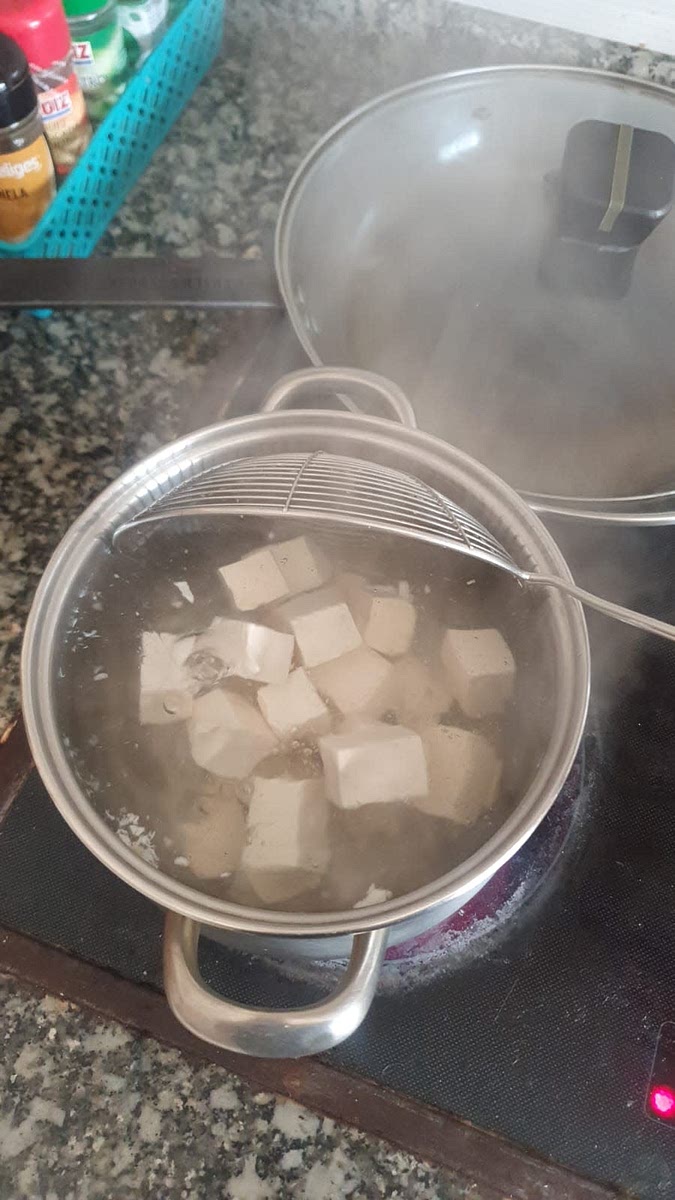 Hervir el tofu cortado en cubos en agua con sal unos minutos y luego dejar reposado en agua fría mientras vamos haciendo el resto.
