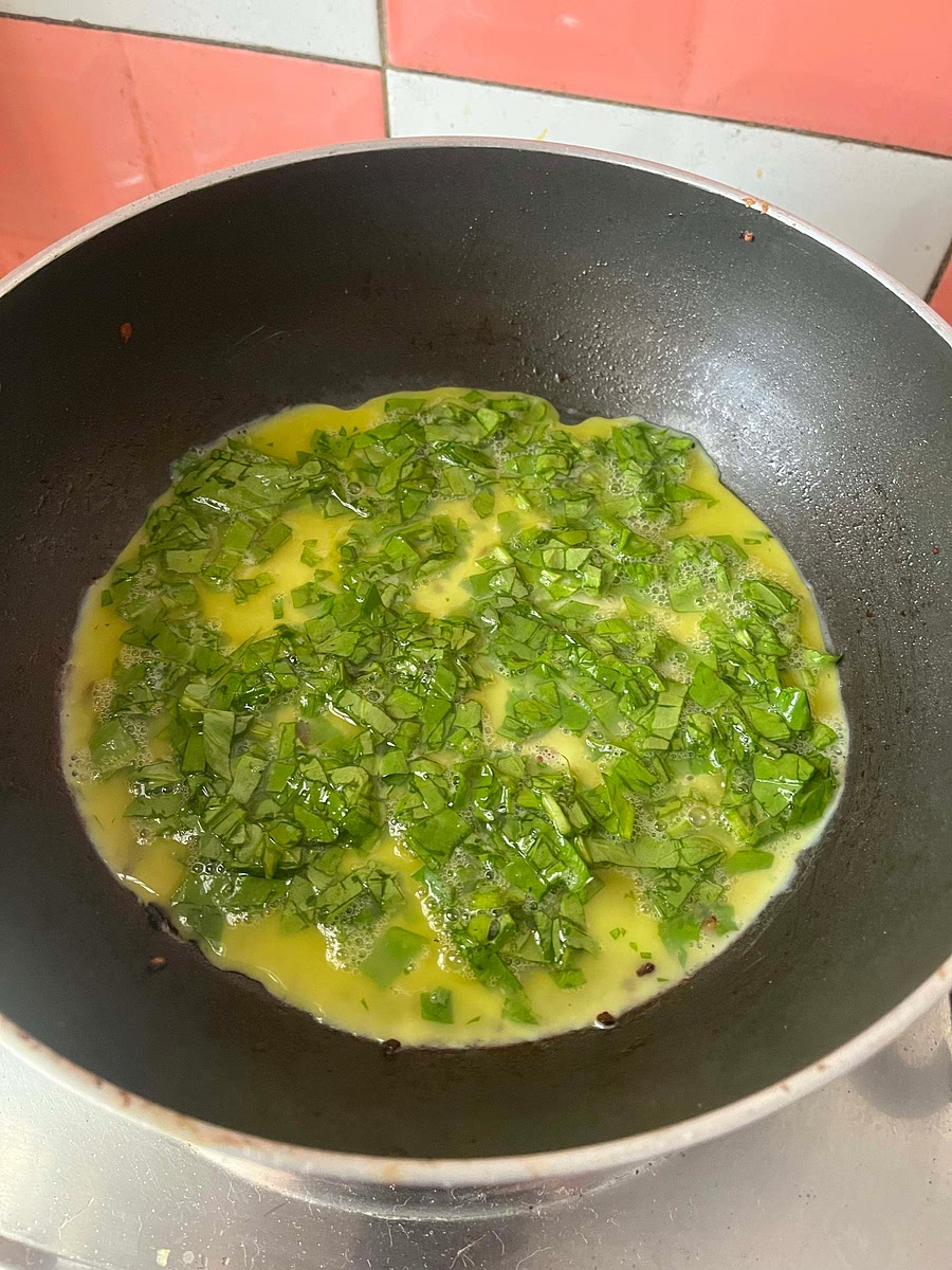 Add 3 eggs, finely chopped spinach, and salt to a bowl. Beat the omelette and pour 1/2 of it on the pan. Spread it out and add a chapati on top. Cook on both sides