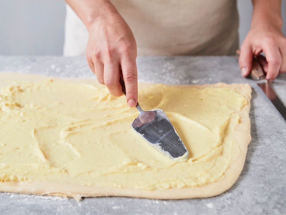 Zwei Backbleche mit Backpapier belegen. Backofen auf 180 Grad Ober-/Unterhitze (Umluft: 160 Grad) vorheizen. Teig auf einer leicht bemehlten Arbeitsfläche zu einem Rechteck (ca. 50 x 35 cm) ausrollen. Pudding esslöffelweise darauf verteilen und mit einem Tortenheber verstreichen. Dabei die Ränder ca. 1 cm frei lassen.