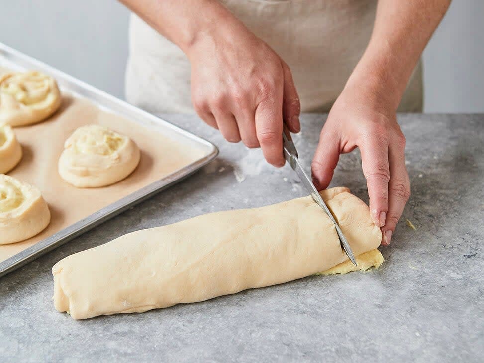 Den bestrichenen Teig von der langen Seite aufrollen und die Teigrolle in ca. 14 Schnecken schneiden. Das Teigende jeder Schnecke auf die Unterseite klappen und mit Abstand auf die Backbleche legen. Im vorgeheizten Backofen ca. 20 Minuten backen. Etwas abkühlen lassen.