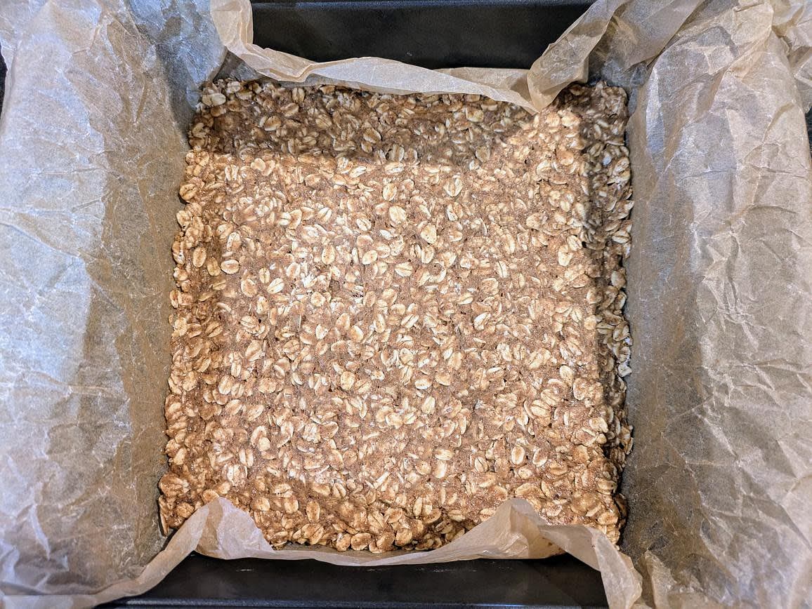 In your pan, spread 2/3 of the oat mixture (320 g) in an even layer to all edges. Either use a silicone spatula, or lightly wet your hands to prevent sticking