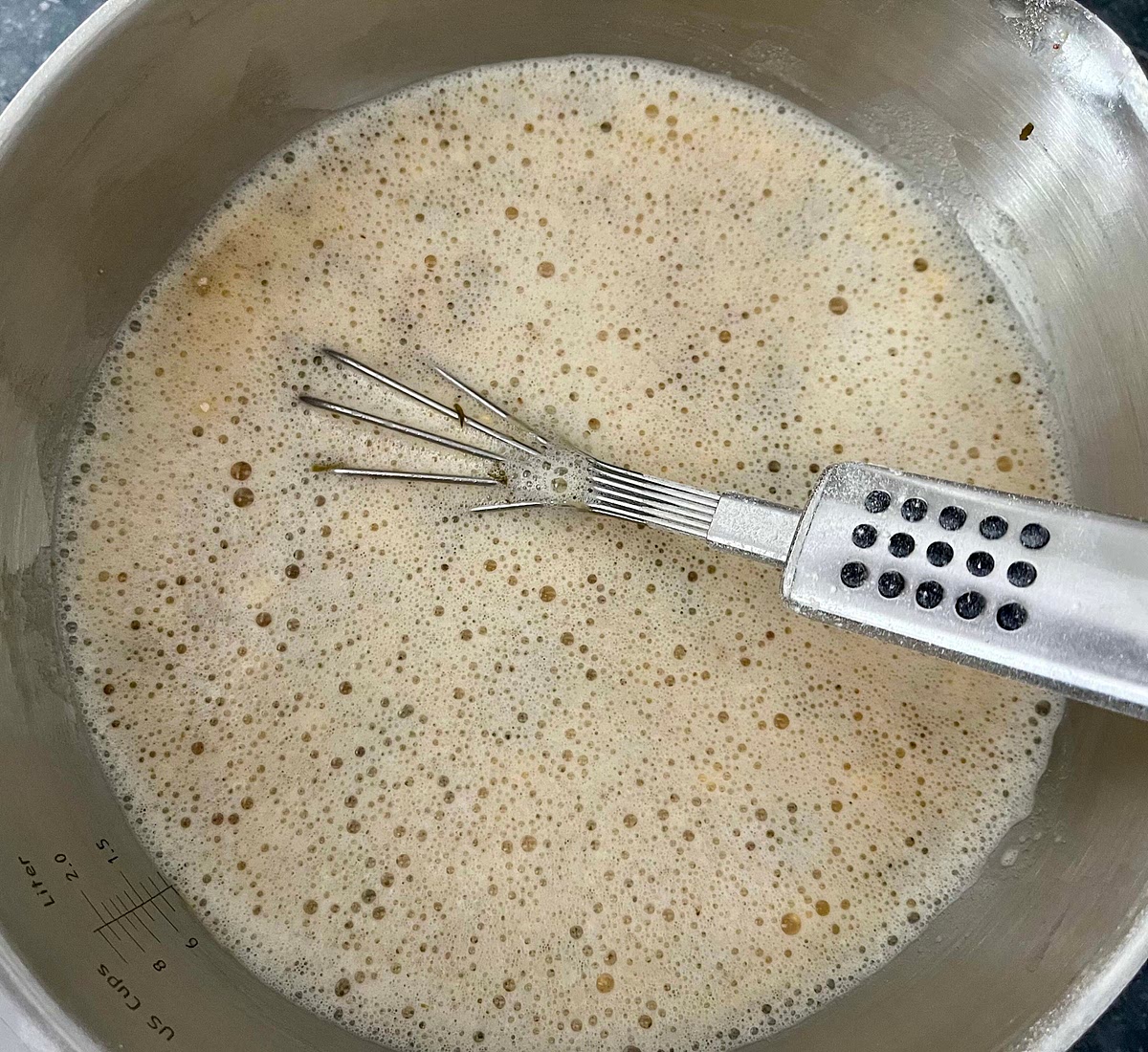 Fold a tea towel in 4 and place the bowl on top so it doesn’t move around. While constantly whisking with one hand, with the other hand sieve in the gram flour, adding it slowly while whisking it in, to prevent forming lumps. You should end up with a very thin watery batter.