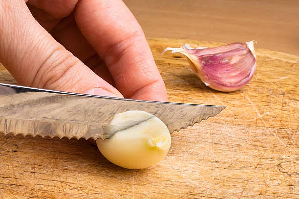 Echa 2 pizca de sal y corta en pedazos el ajo e introducelo en el recipiente