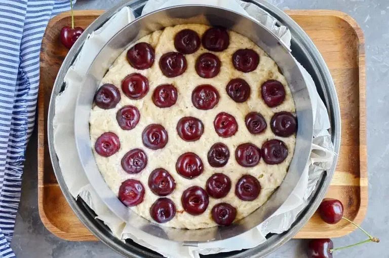 Pour the mixture, evenly, into the tin. Remove the stalks and stones from the cherries and scatter them over the top of the mixture. Gently press them into the batter.