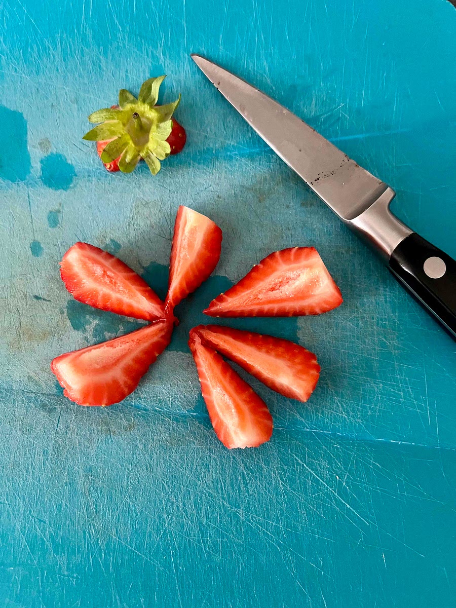Dry the strawberries with a tea towel. Cut off the leaves, then place each strawberry cut side down on a chopping board and cut them in wedges. I cut the larger ones in 6 and the smaller ones in 4.
