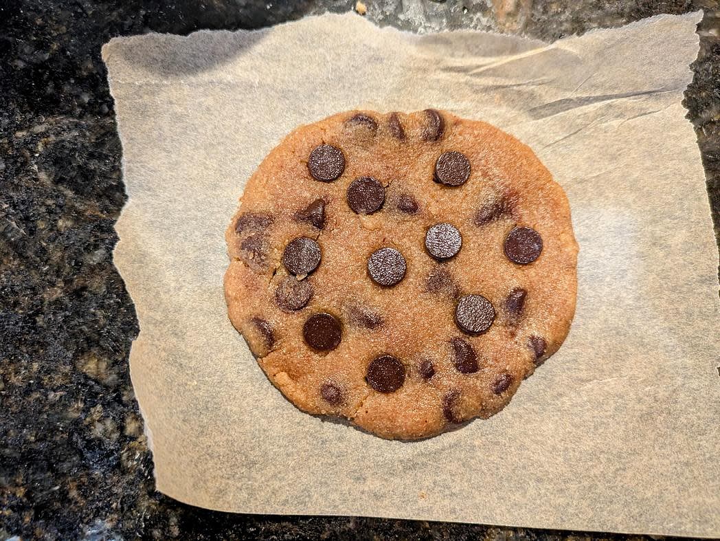 Flatten the cookie onto a small piece of parchment paper, shape into a circle, and top with your remaining chocolate chips
