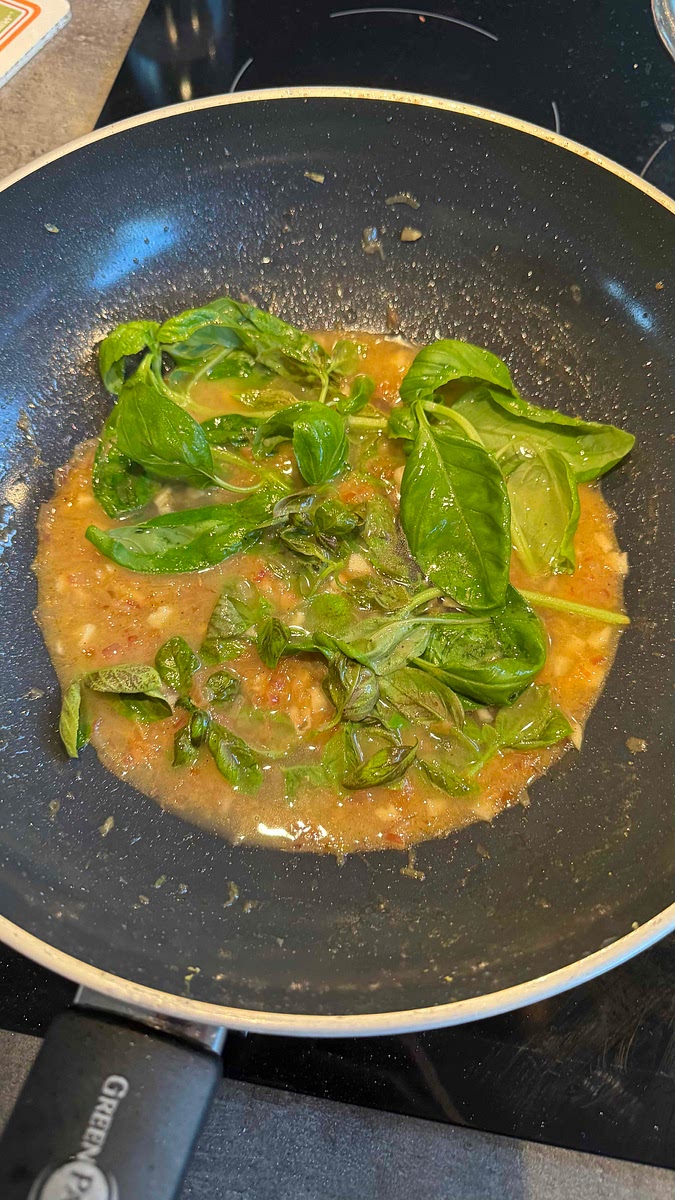 Baisser le feu et placer les branches de basilic entières dans la poêle. Les retirer des qu’elles commencent à foncer.