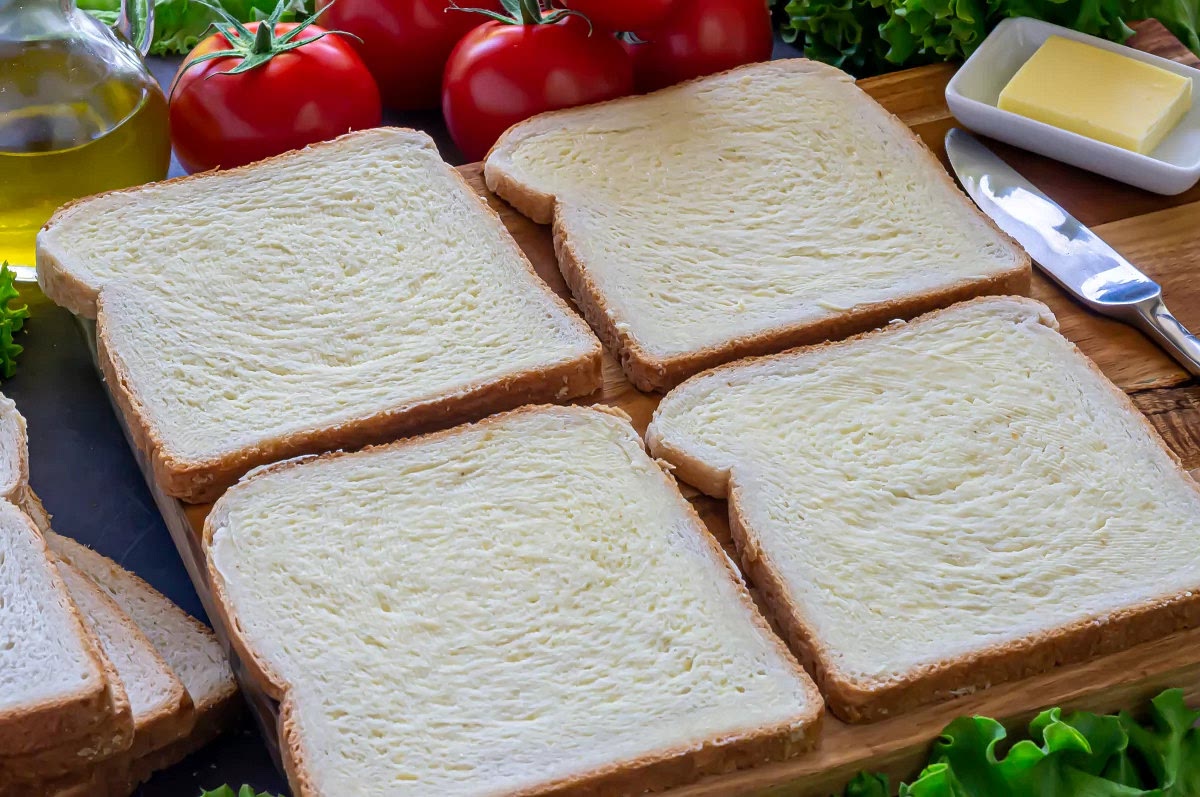 Lo primero de todo, comenzar untando una fina capa de mantequilla sobre las rebanadas de pan por uno de los lados. La mantequilla deberá estar a temperatura ambiente y bien blanda para que se reparta mejor y se necesite poca cantidad. Reservar.