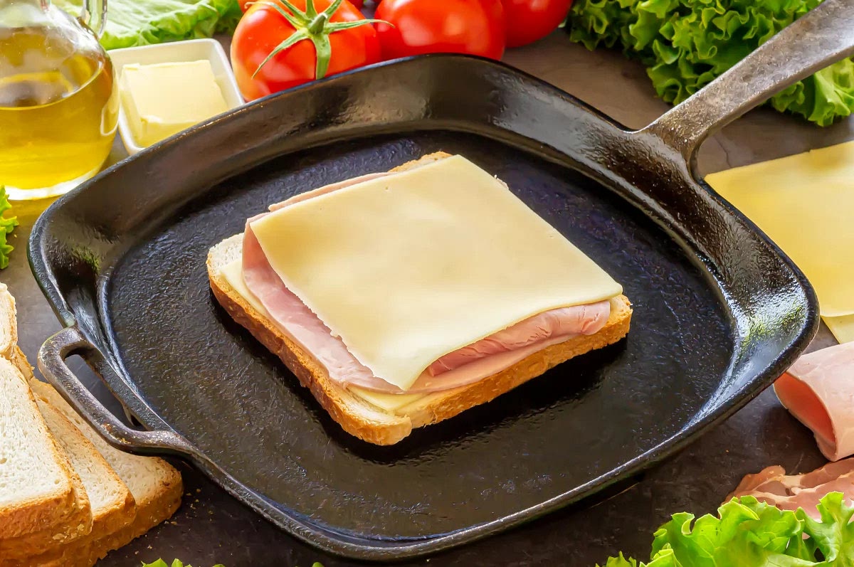 Formar un sándwich intercalando dos lonchas de queso entre una loncha de jamón. Cortar ésta última de tal manera que no sobresalga. Hay que dejar los lados de la mantequilla hacia afuera.