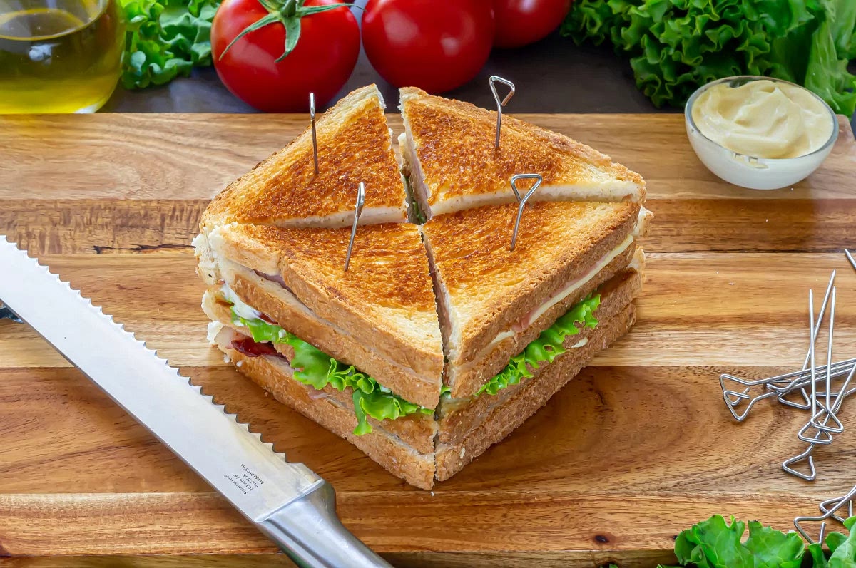 Juntar los dos sándwiches para formar uno solo, cortarlo en triángulos y sujetar cada porción con un palillo o palo para mini brochetas.