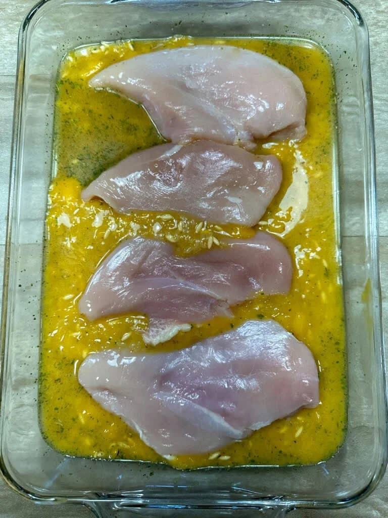 Next, place the chicken in the casserole dish and spoon a little of the liquid over the chicken breasts.