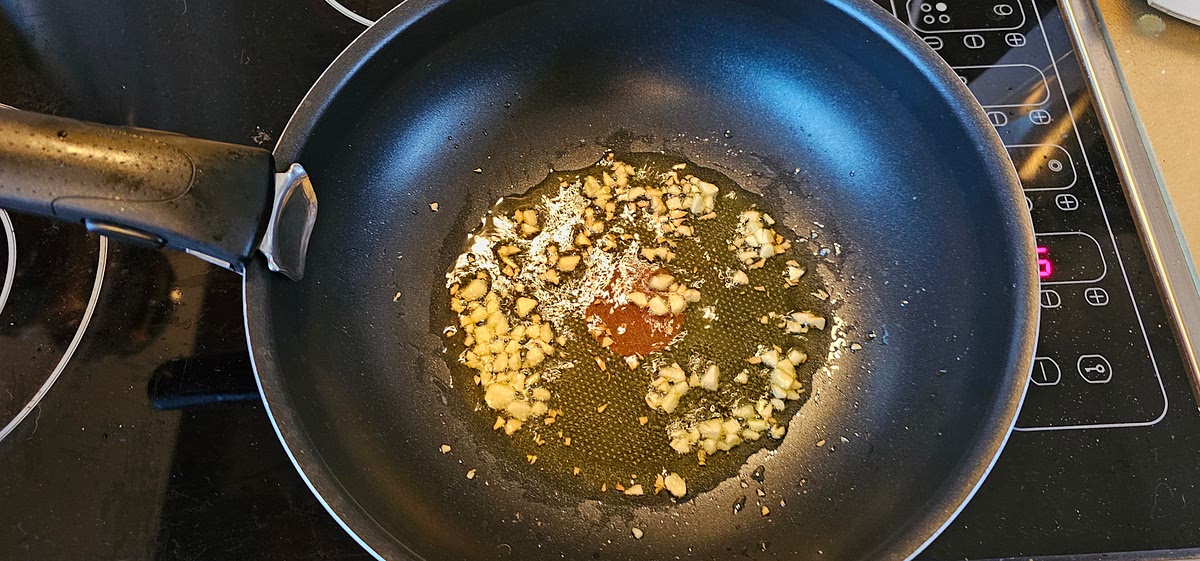 Tagliare fini i due spicchi d'aglio e farli rosolare con l'olio.