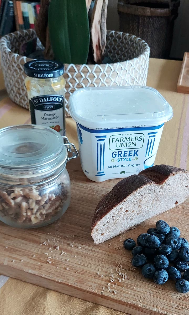 Spread a thin layer of orange marmelade on the bread, then add a layer of yoghurt, and top it with blueberries and walnuts.