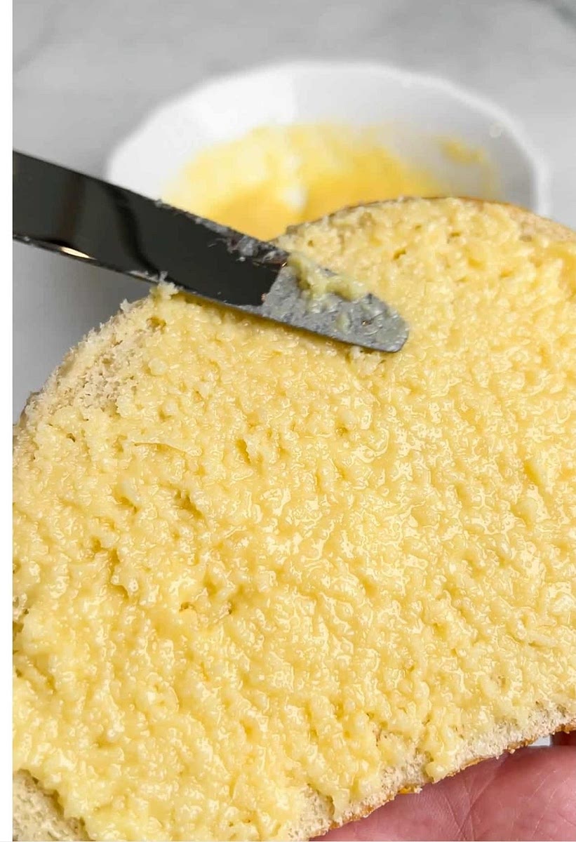 To build the grilled cheese sandwich, spread the garlic parmesan butter on the outside of each piece of bread. Add in two slices of sharp cheddar and one slice of mozzarella cheese to the non-buttered side.