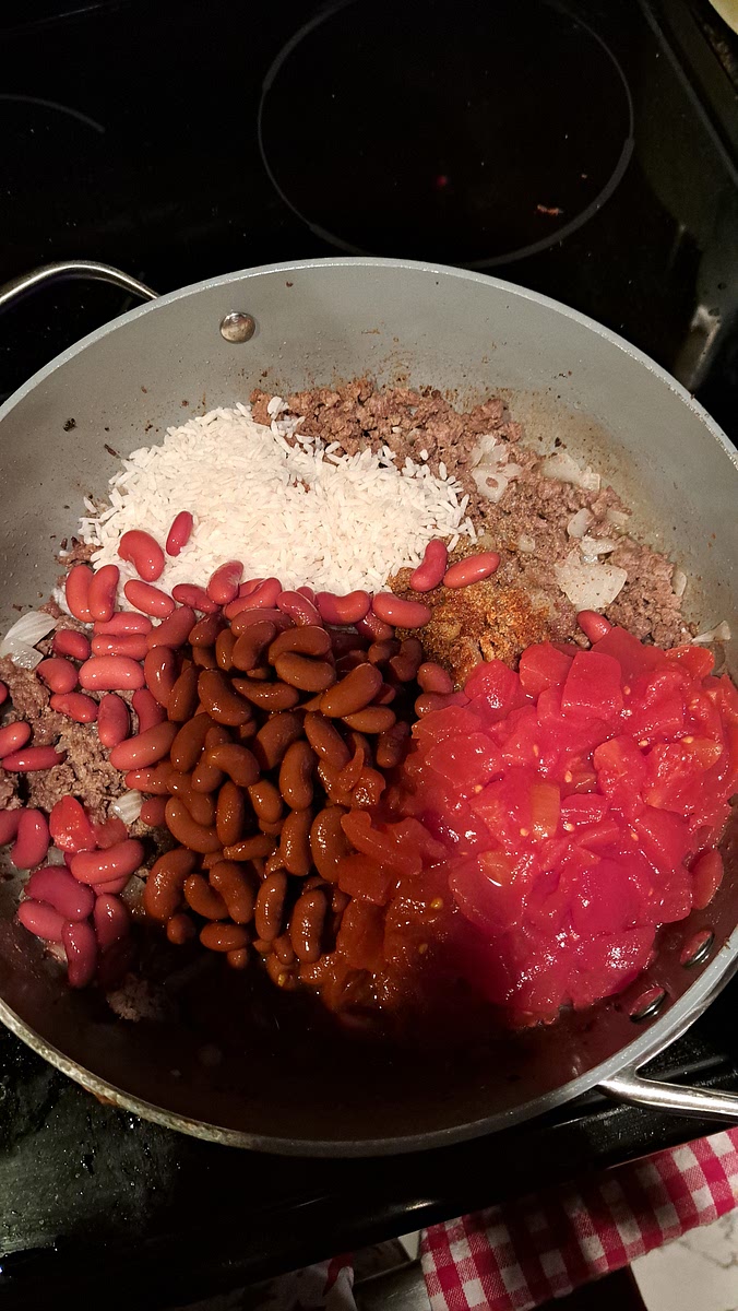 Stir in the undrained tomatoes, undrained beans, rice, water, green pepper, chili powder, salt, and garlic salt.