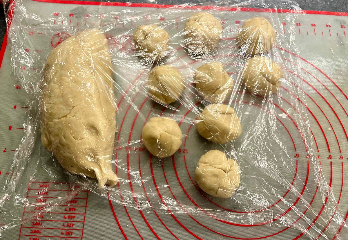 Once rested, unwrap the ball and keep the cling film. Cut the dough and make balls slightly larger than than a golf ball (about 50g each) and cover them with the cling film. You should get 20-22 dough balls.