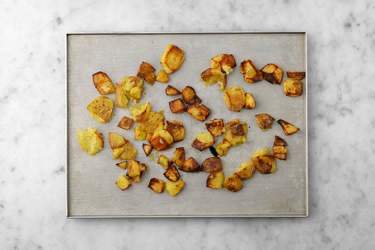 Meanwhile, in a large bowl, combine a good squeeze of lemon juice with the sugar and olive oil for the dressing. When the potatoes have cooked for 20 mins, remove them from the oven. Use the bottom of a bowl or pan to lightly crush each potato. Drizzle the smashed potatoes with more oil, and return to the top shelf of your oven until crispy and golden, 10-15 mins.