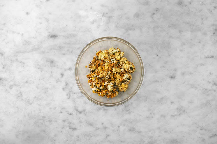 When the cauliflower is roasted, drizzle over the honey and toss to coat. When everything's ready, add the cauliflower and sweetcorn to the lemon dressing. Crumble in the feta cheese, season with salt and pepper, then toss everything together.