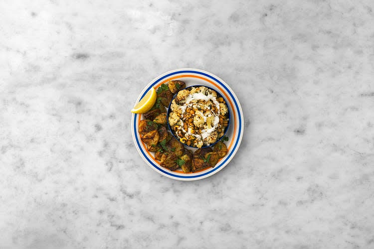 Share the roasted cauli salad between your plates. Drizzle over the soured cream. Serve the smashed potatoes alongside. Serve with any remaining lemon wedges for squeezing over. Enjoy!