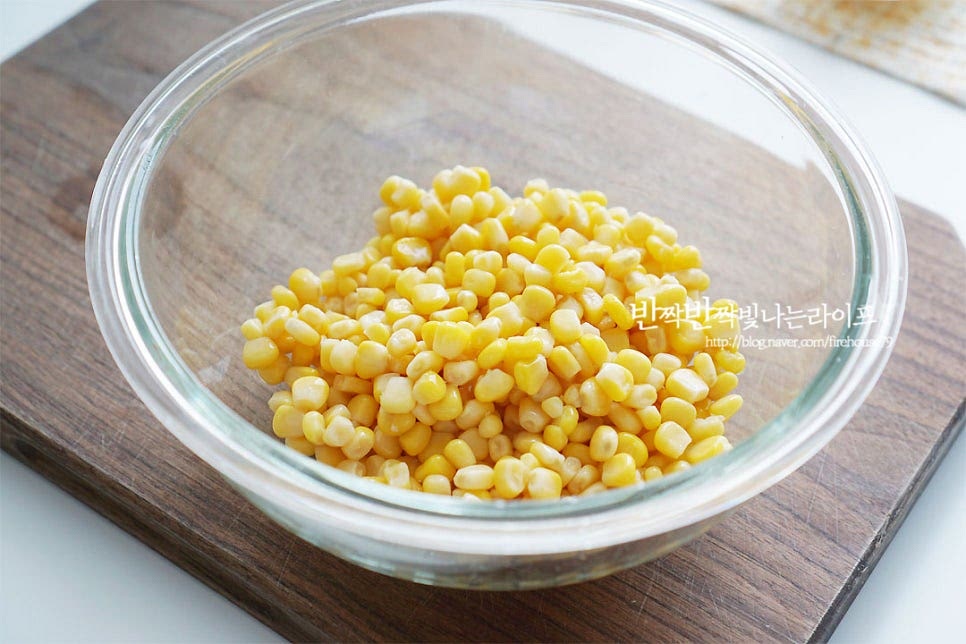 큰 볼에 수분을 털어낸 걸 담아요. 수분은 가볍게 털어주면 됩니다. 튀김가루 1/2종이컵을 넣어줍니다. 바삭한 식감을 위해 튀김가루를 넣어주었는데 전분가루 또는 부침가루를 넣으셔도 됩니다. 가볍게 버무려준 뒤 물로 농도를 조절하여 줍니다. 옥수수 알갱이로 전을 만들 때 식감을 살려주기 위해 가루는 재료가 어우러질 정도로만 물 역시 묽지 않게 넣어줍니다. 재료 양에 따라 튀김가루와 물을 가감해요. 재료가 서로 어우러질 정도의 걸쭉한 농도로 반죽을 해줍니다. 이대로 구워도 맛있지만 모짜렐라 피자치즈를 더해주면 고소한 풍미가 더 좋답니다. 치즈는 50g 정도 넣고 소금 약간 넣고 간을 해요. 콘옥수수전을 먹었을 때 약간 짭조름하여 연유와 단짠의 조합을 이루도록 해주었어요.