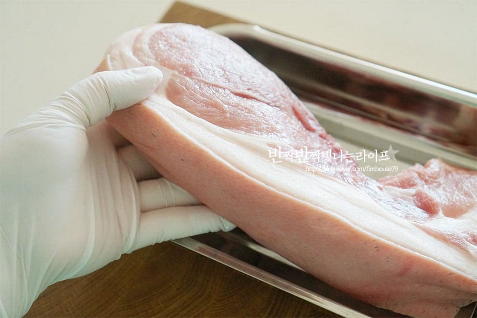 앞다리살은 돼지고기 부위 중에서도 담백하고 쫄깃한 식감이 맛이 좋아요. 지방함량이 적은 편이며 육단백질이 풍부하여 수육을 삶았을 때 부담 없이 먹기 좋습니다. 쫄깃한 식감을 위해 껍질이 붙은 흑돼지로 준비했어요. 크기에 따라 2~3등분으로 잘라줍니다. 신선한 것이라 가볍게 겉의 핏물을 제거한 뒤 삶아주었는데 냄새에 예민하다면 찬물에 담가 핏물을 빼주셔도 좋습니다. 앞서 말씀드린 것과 같이 돼지수육 같은 경우 누린내를 잡아주는 것이 요리의 중요한 포인트인데요. 육질을 부드럽게 해주면서 잡내를 잡아줄 수 있도록 몇 가지 부재료를 첨가해 줍니다. 사과는 가운데 씨를 제거한 뒤 8등분으로 잘라주고, 양파와 대파는 큼직하게 썰어줍니다. 통마늘은 꼭지를 제거하고 생강은 껍질을 깎아 준비해 주었습니다.