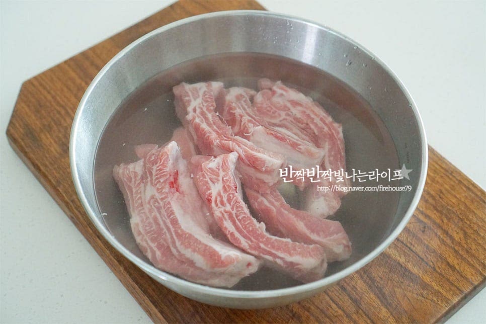 뼈에 붙은 고기이기 때문에 찬물에 담가 핏물을 빼줍니다. 중간에 물을 두세 번 갈아주어 30분 핏물을 제거해 주었습니다. 냄비에 물 1L와 향신 재료를 넣어줍니다. 대파 초록 부분, 월계수잎, 통후추를 넣고 팔팔 끓으면 고기와 생강술(청주)를 넣어줍니다. 육즙이 새어 나오지 않도록 끓을 때 넣어주었어요. 센 불로 대략 10분 정도 데쳐줍니다. 뼈 부분을 눌러보았을 때 핏물이 나오지 않는 정도면 됩니다. 찬물에 헹구어 체에 밭쳐 물기를 털어줍니다.