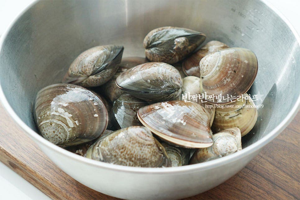 바지락이나 동죽 같은 종류에 비해 크기가 크고 국물이 진하게 우러나요. 조개요리는 탕, 찜, 구이 등 다양하게 맛볼 수 있지만 지금같이 찬바람 부는 계절엔 뜨끈한 국물 탕 요리가 제일이죠. 겉을 만져보면 미끄덩한데요. 굵은소금 1 큰 술을 넣고 가볍게 씻어 헹구어 줍니다. 백합조개 해감은 간단해요. 소금물에 30분~1시간 정도 담가주면 이물질을 뱉어내는데요. 보통 기본 손질하여 팔기 때문에 직접 캔 것이 아닌 이상 1시간 이내로 해감하여 주면 됩니다. 소금물에 담글 때는 빛이 들어가지 않도록 신문지나 검은 봉지를 덮어 어둡게 해주면 됩니다.