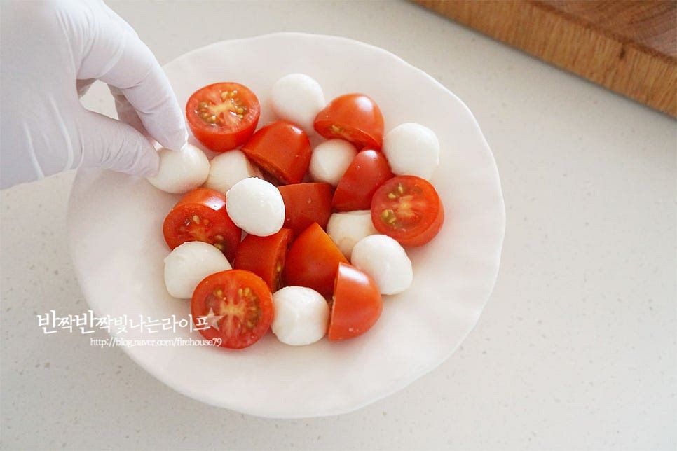 접시에 방울토마토와 치즈를 어우러지게 담아줍니다. 바질잎과 레몬 슬라이스를 올려 완성해요. 마지막으로 발사믹소스를 골고루 뿌려 완성합니다.