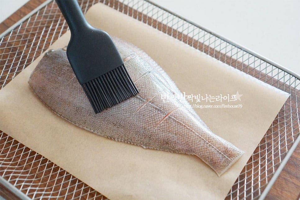 에프 바스켓에 종이호일을 깔고 가자미를 올려 식용유를 발라줍니다. 구울 때 껍질이 벗겨지기 쉬운 생선이라 식용유를 넉넉히 고르게 발라주었어요. 팬에 구울 때는 밀가루나 전분가루 옷을 입혀주시면 식감도 바삭하고 껍질도 벗겨지지 않아요. 앞뒤로 식용유를 발라 준비했습니다.